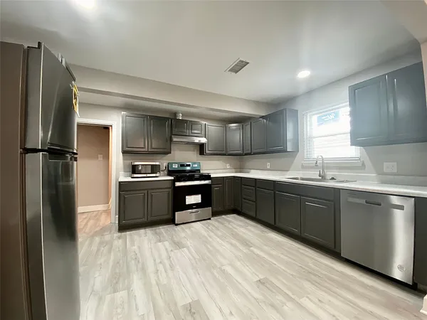 a kitchen with granite countertop a refrigerator stove and sink