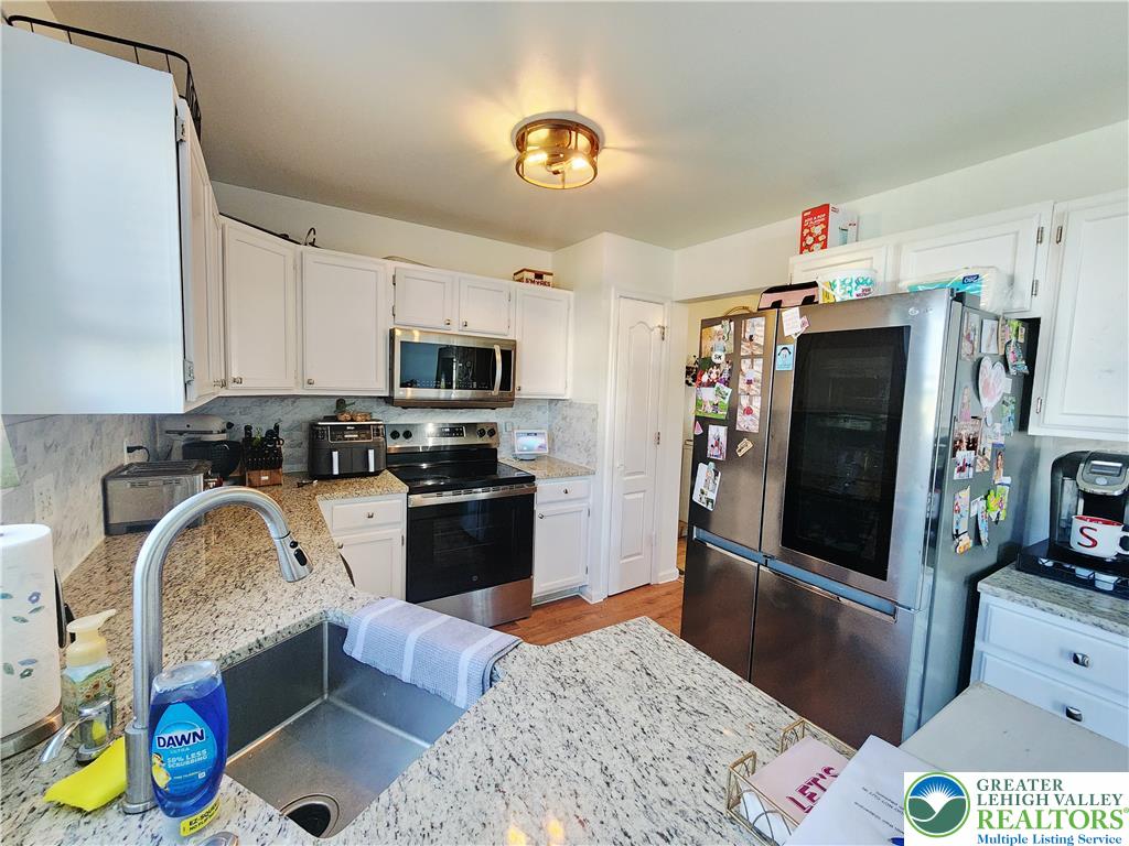 237 Ridings Circle Macungie, PA 18062 - Photo 20 of 70 Gleaming granite countertops pair beautifully with white cabinetry and warm wood flooring.