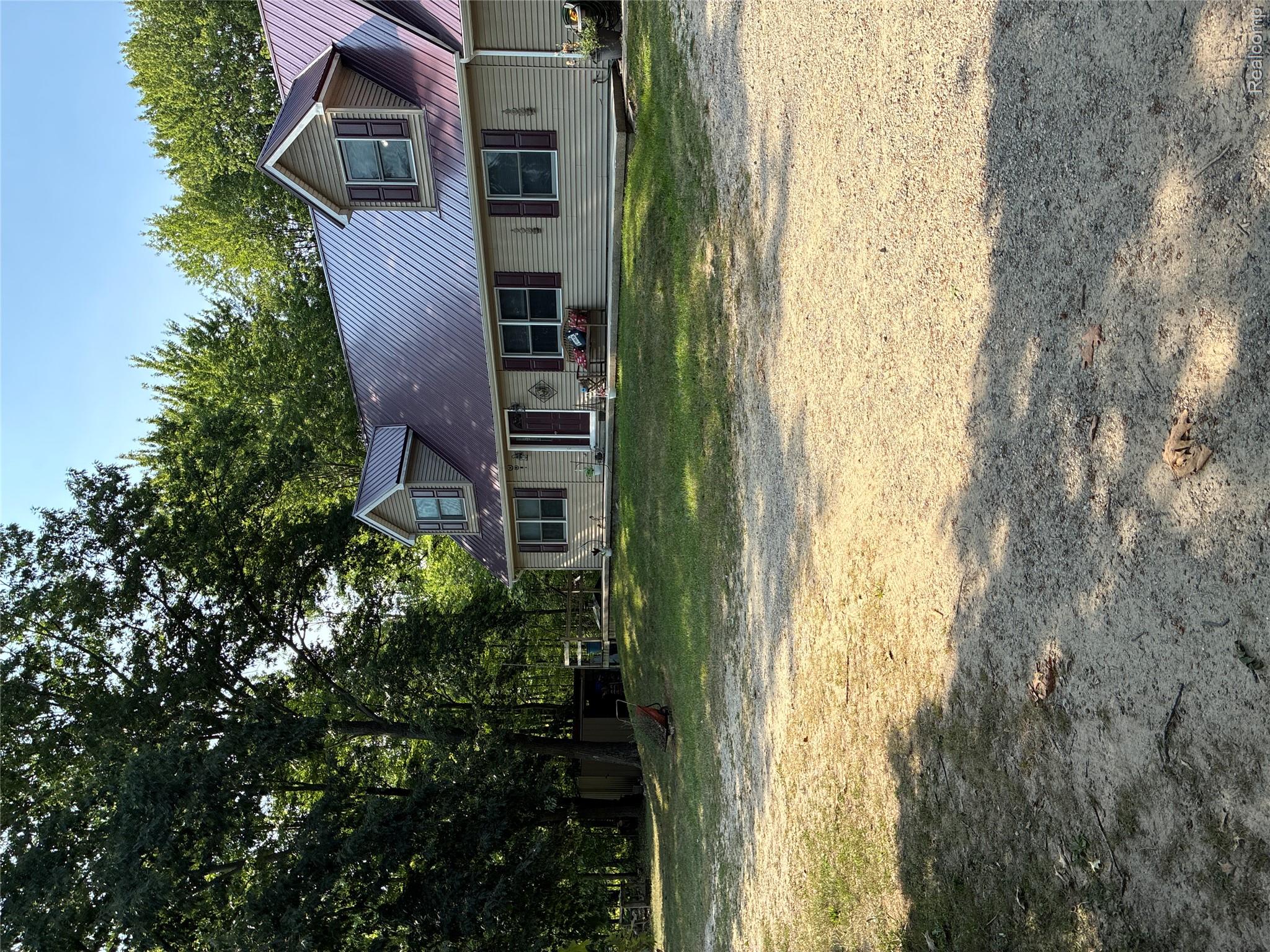 Beige siding exterior with a red metal roof and dormer windows