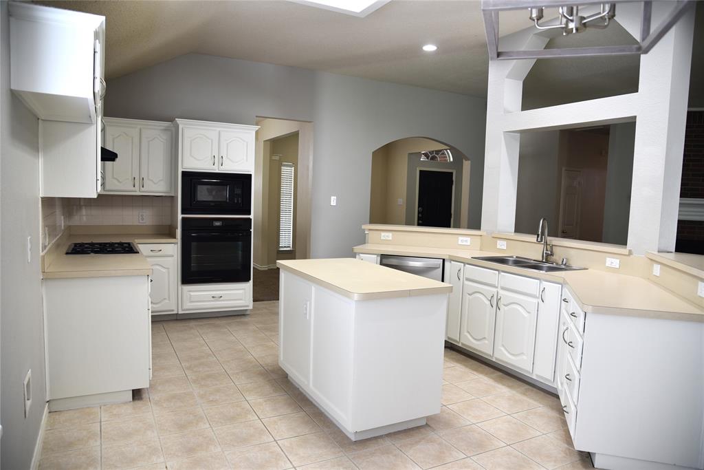1526 Pebblestone Court Allen, TX 75002 - Photo 7 of 28 Kitchen featuring an island, white cabinetry, light-toned countertops, tile flooring, and integrated black appliances
