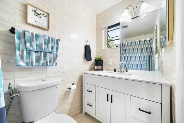 a bathroom with a granite countertop sink mirror vanity and toilet