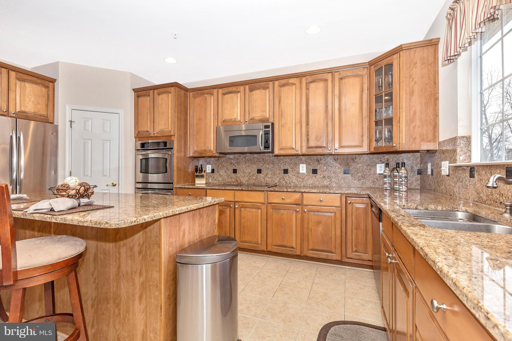 14513 Bubbling Spring Road Boyds, MD 20841 - Photo 14 of 57 a kitchen with stainless steel appliances granite countertop a sink a stove and white cabinets
