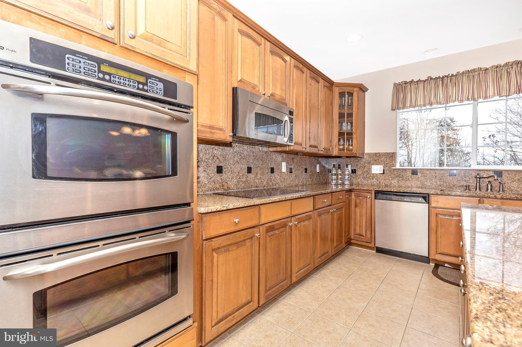 14513 Bubbling Spring Road Boyds, MD 20841 - Photo 15 of 57 a kitchen with stainless steel appliances granite countertop a sink a stove a microwave a counter space and cabinets
