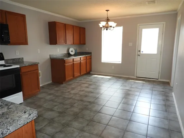 a kitchen with granite countertop a stove a sink a window and counter space
