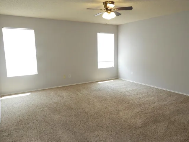 an empty room with a window and ceiling fan