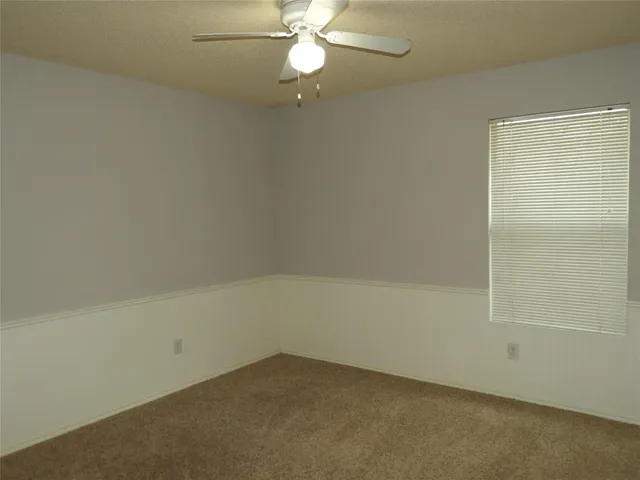 an empty room with a ceiling fan and a window