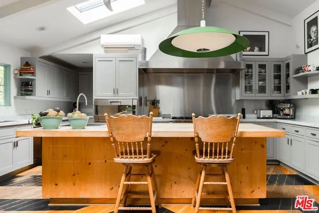 a kitchen with stainless steel appliances granite countertop a dining table chairs and a refrigerator