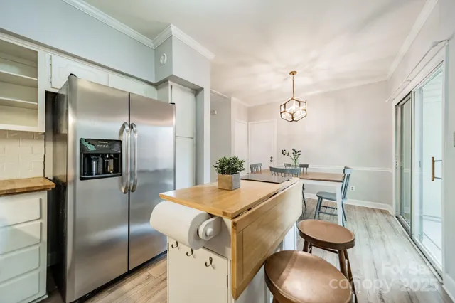 a kitchen with stainless steel appliances refrigerator dining table and chairs