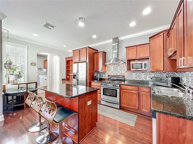 a very nice looking kitchen with granite countertop a large counter top space a sink stainless steel appliances and cabinets