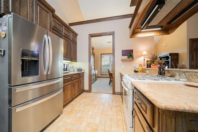 a kitchen with stainless steel appliances granite countertop a refrigerator a stove and a sink with wooden floor