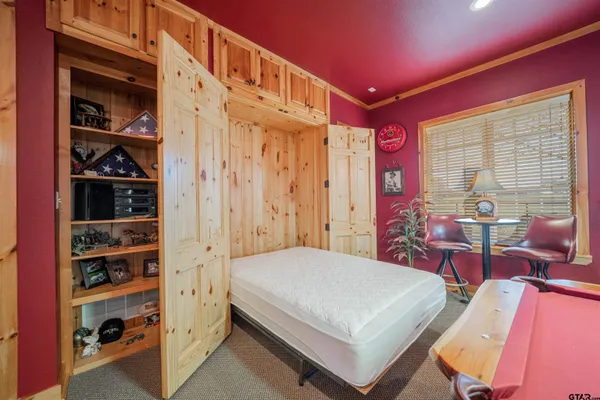 a bedroom with a bed a bookshelf and a window