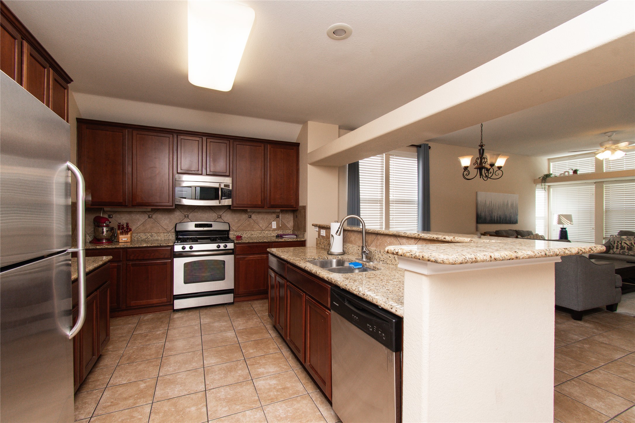 421 Shadow Point San Marcos, TX 78666 - Photo 24 of 24 Kitchen with stainless steel appliances, light stone counters, a chandelier, decorative backsplash, and open floor plan
