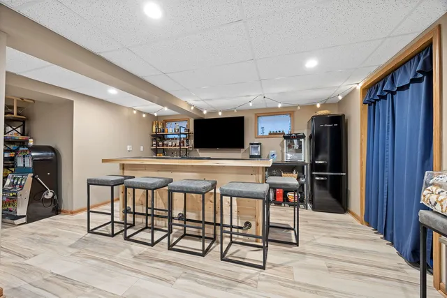 a room with stainless steel appliances kitchen island granite countertop a refrigerator a stove top oven a dining table and chairs with wooden floor