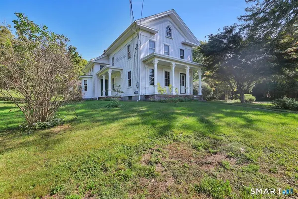 a view of a house with a big yard and large trees