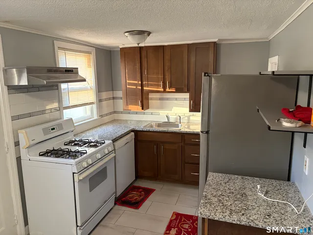 a kitchen with granite countertop a sink stove and refrigerator
