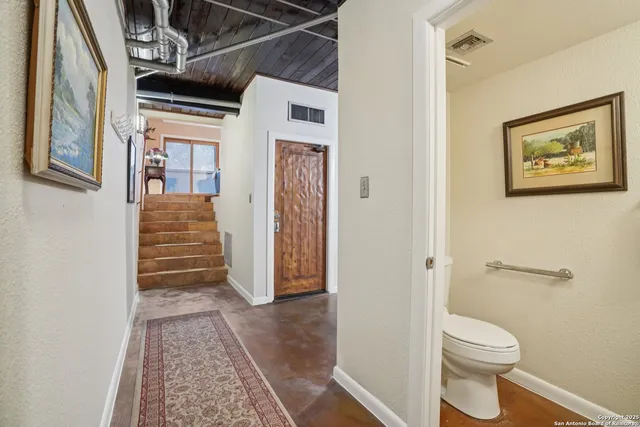 a view of a hallway with wooden floor and bathroom