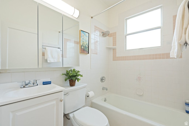 673 East 700 South Springville, UT 84663 - Photo 25 of 43 Bathroom featuring white tiled walls with a light pink accent border, a built-in tub with a shower head, and a window for natural light