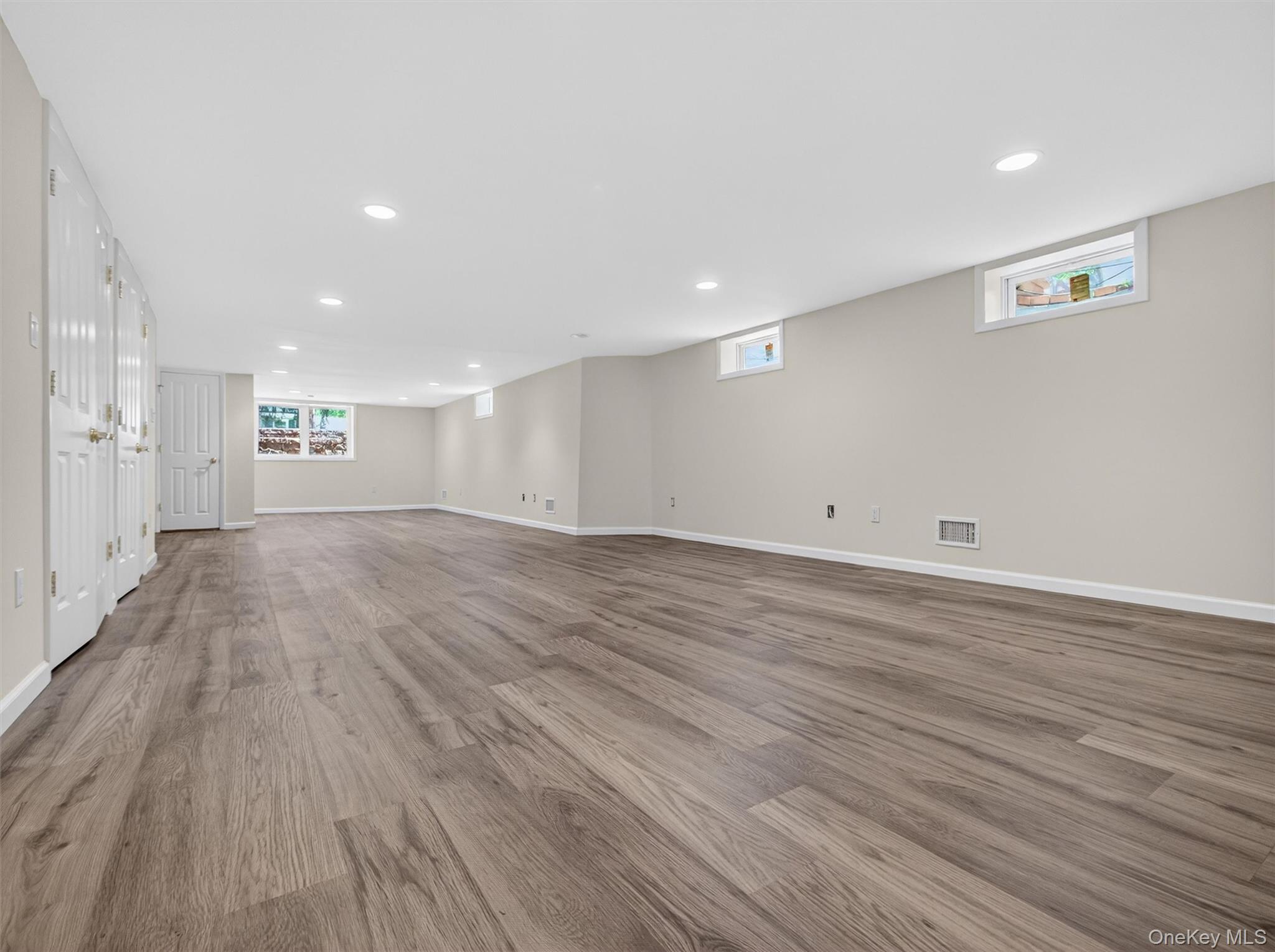 19 Buckingham Road Nanuet, NY 10954 - Photo 27 of 39 Expansive lower-level room featuring laminate flooring, recessed lighting, and natural light from multiple windows.