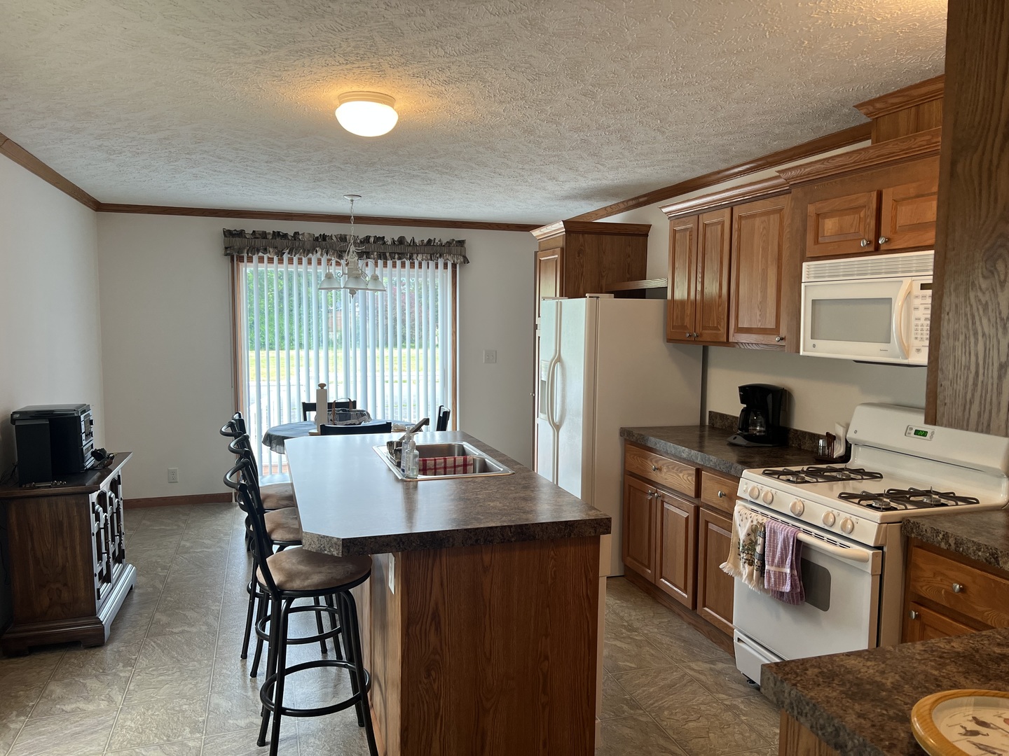 405 James Road Elwood, IL 60421 - Photo 5 of 27 a kitchen with stainless steel appliances granite countertop a stove a refrigerator a sink dishwasher a dining table and chairs with wooden floor