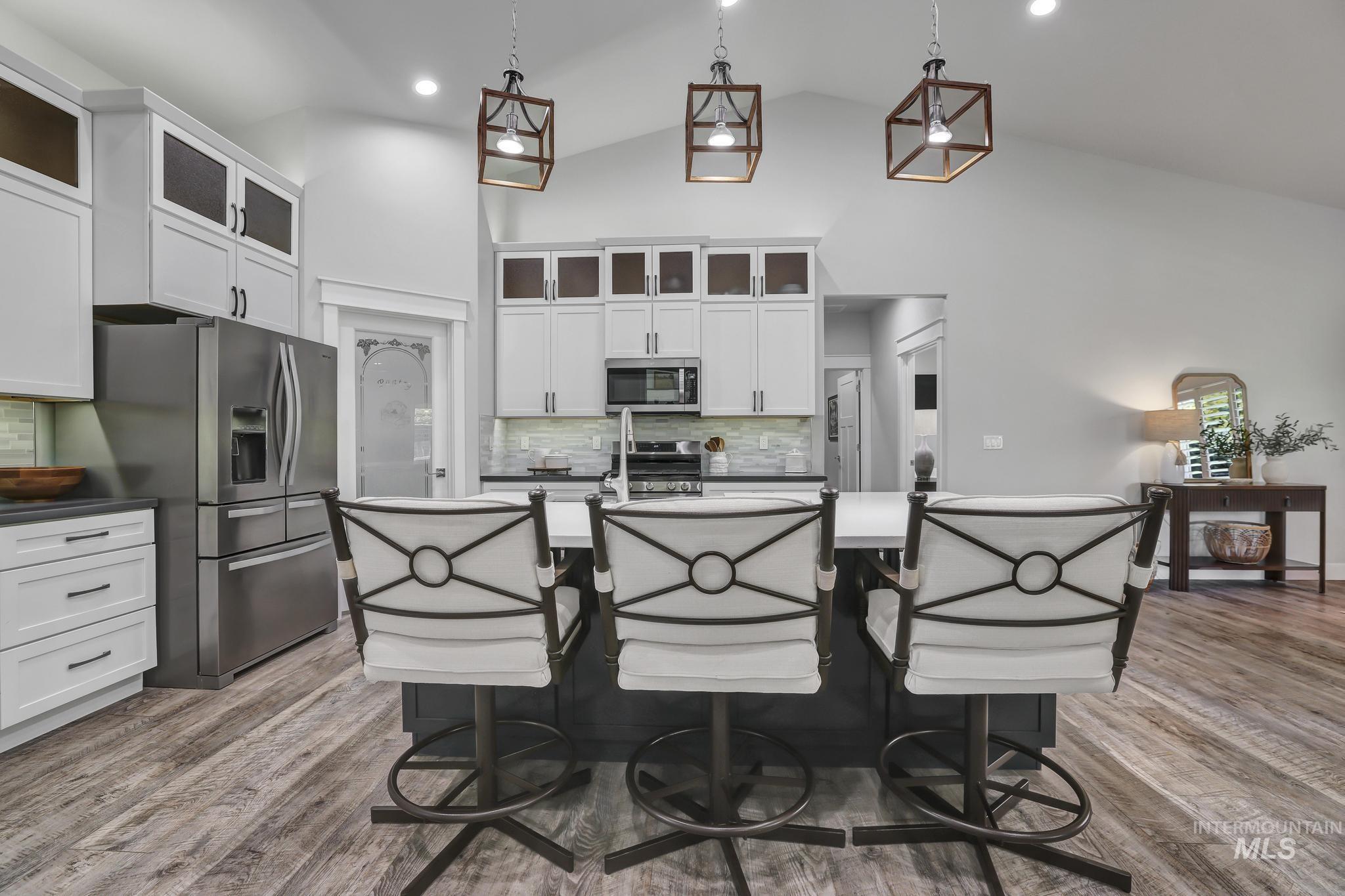 1937 Tamarack Loop Twin Falls, ID 83301 - Photo 12 of 50 Kitchen featuring a vaulted ceiling with pendant lighting, white cabinetry with dark hardware, stainless steel appliances, and wood-finish flooring