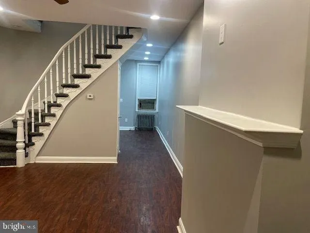 an empty room with wooden floor closet and windows