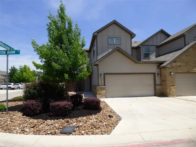 a view of a house with a yard plants and large tree
