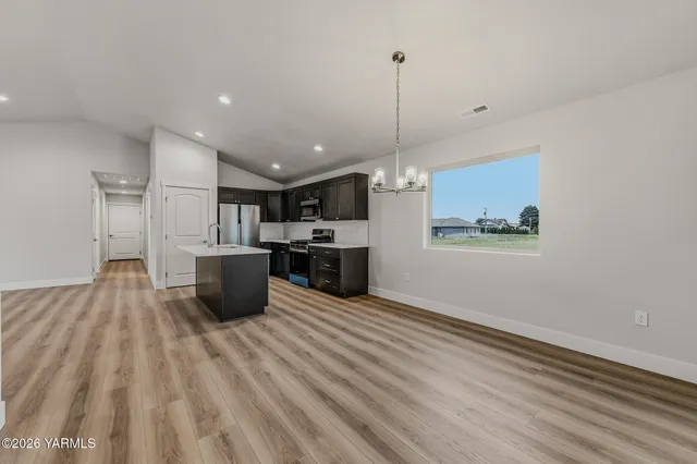 a large kitchen with stainless steel appliances kitchen island a large counter top a sink a stove and a refrigerator