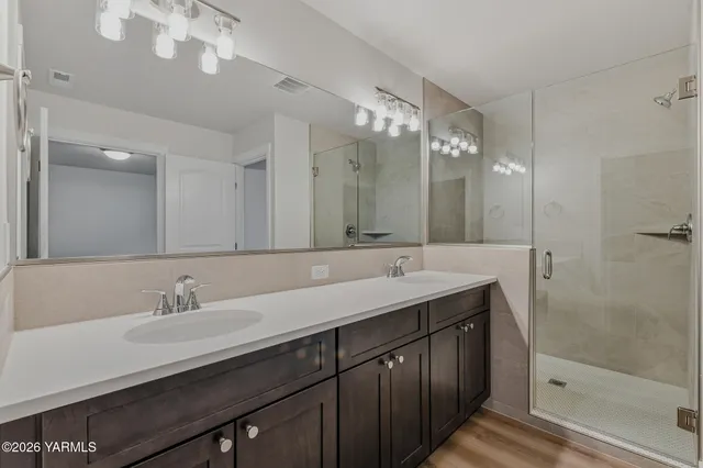 a bathroom with a double vanity sink mirror and shower