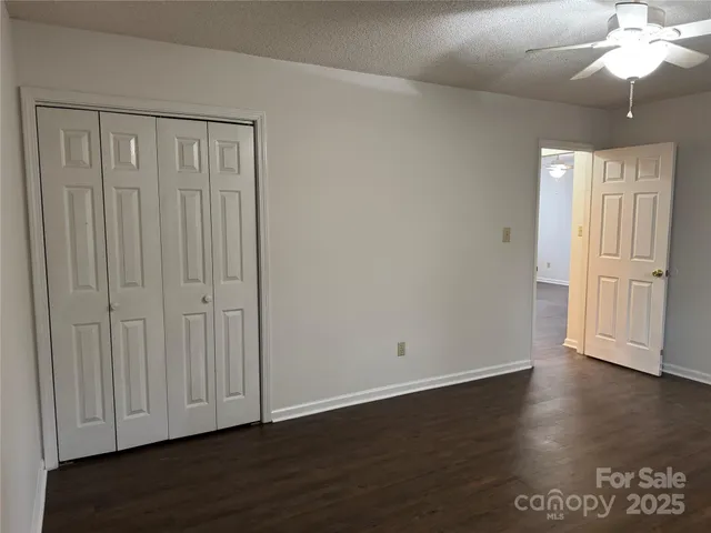 a view of a small house with a yard and wooden fence