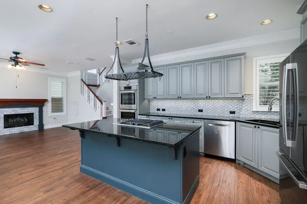 a kitchen with stainless steel appliances granite countertop a sink a stove and a wooden floors