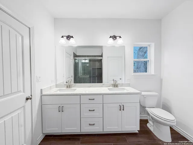 a bathroom with a double vanity sink a toilet and a mirror