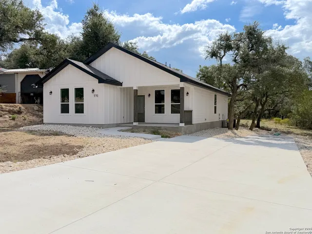 a view of a white house with a yard and large trees