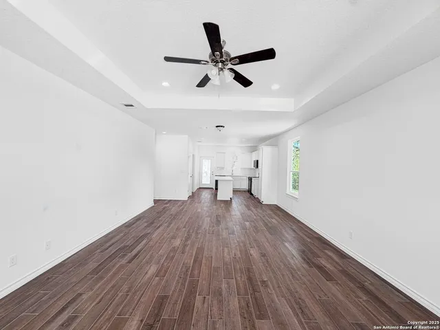 a view of empty room with wooden floor and ceiling fan