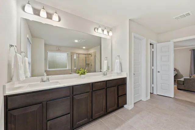a bathroom with double vanity sinks a vanity a lamp and a mirror
