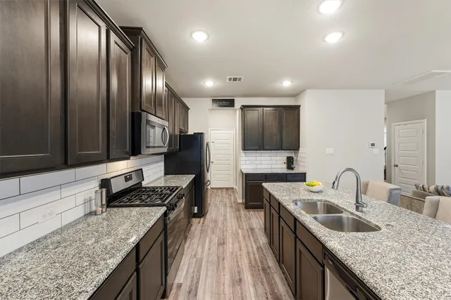 a kitchen with stainless steel appliances granite countertop a sink stove and refrigerator