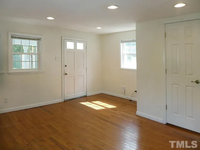 a view of an empty room with window and wooden floor