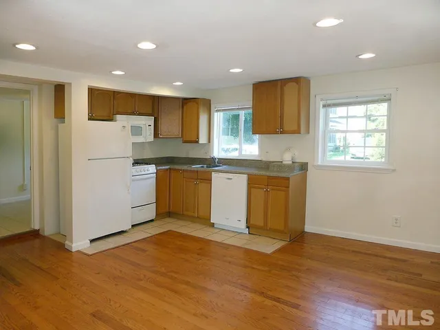 a kitchen with stainless steel appliances granite countertop a refrigerator a sink dishwasher and a stove with wooden floor