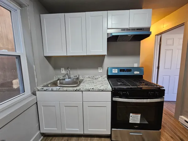 a kitchen with stainless steel appliances granite countertop white cabinets and a stove
