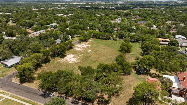 an aerial view of residential houses with outdoor space and trees