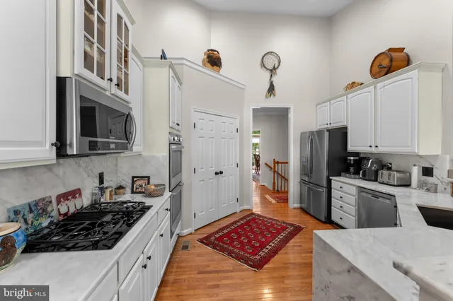 a kitchen with stainless steel appliances a stove a sink a refrigerator wooden floor and cabinets