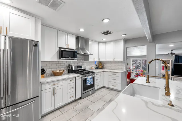 a kitchen with stainless steel appliances a dining table chairs stove refrigerator and cabinets