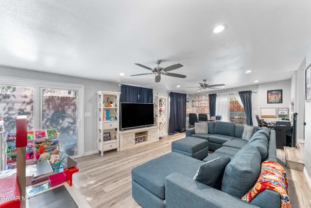 a large white kitchen with kitchen island a stove a sink a dining table and chairs with wooden floor