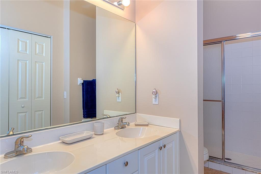 4970 Deerfield Way, Unit F203 Naples, FL 34110 - Photo 13 of 23 a bathroom with a granite countertop sink and a mirror