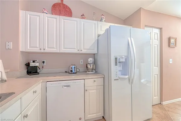 a kitchen with stainless steel appliances granite countertop a refrigerator and a white cabinets