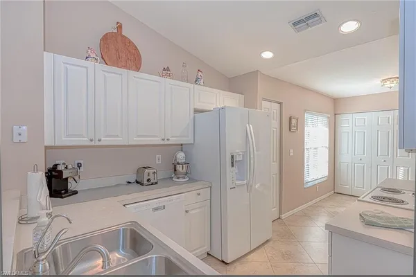 a kitchen with stainless steel appliances granite countertop a refrigerator sink and white cabinets