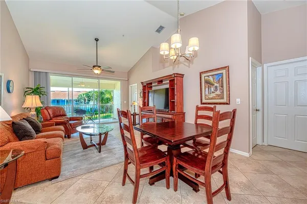 a view of a dining room with furniture a chandelier and large windows