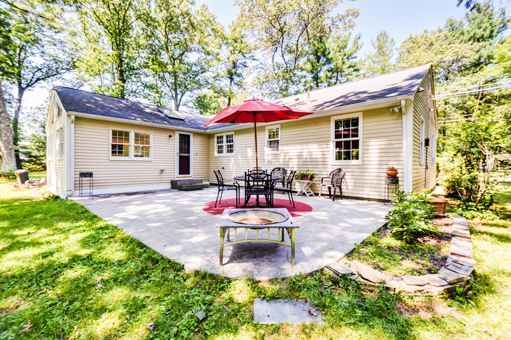 174 New Estate Road Littleton, MA 01460 - Photo 23 of 30 a view of a backyard with table and chairs under an umbrella