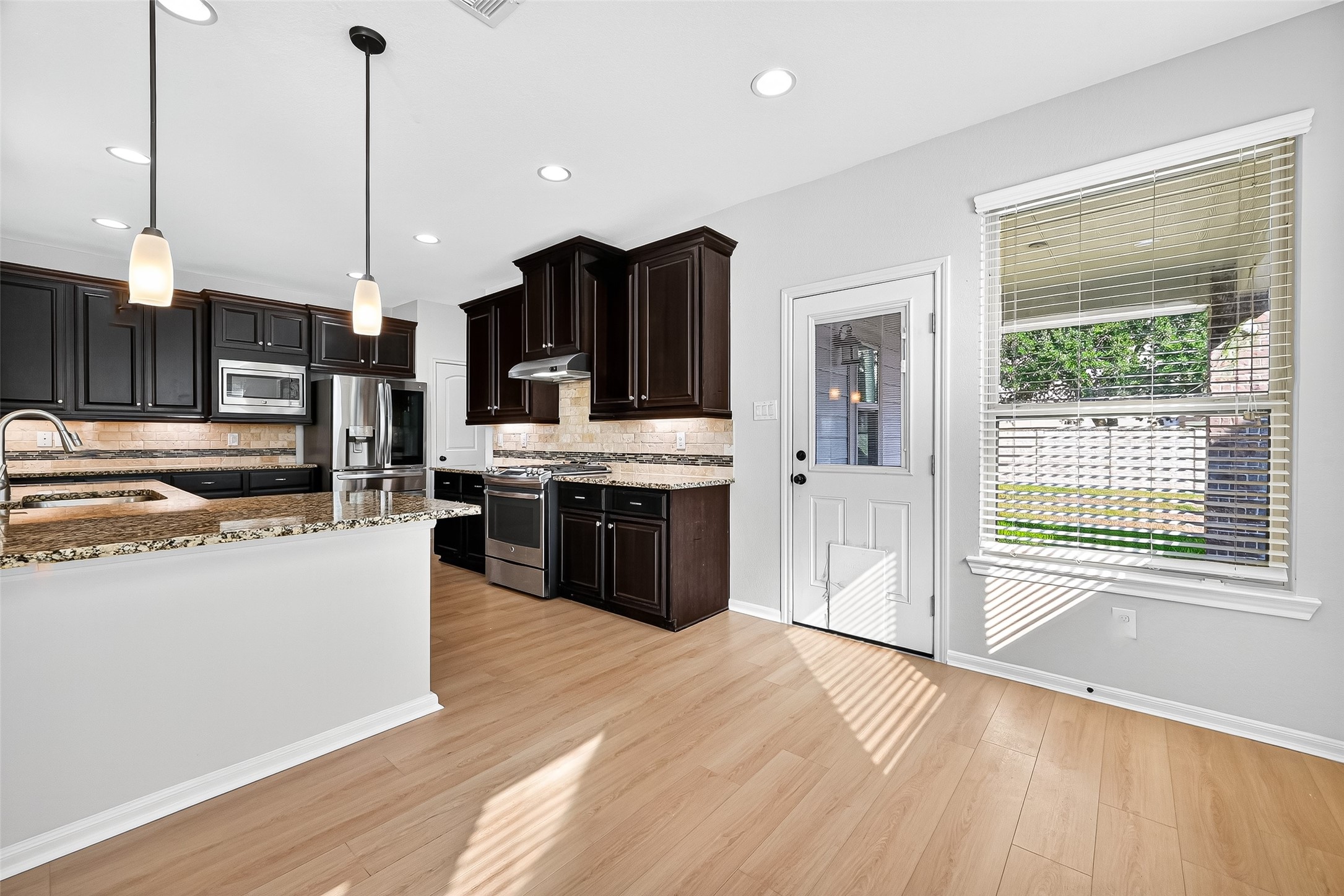 1531 Kent Valley Lane Rosenberg, TX 77471 - Photo 11 of 37 a large kitchen with stainless steel appliances granite countertop a stove a sink dishwasher a refrigerator and a kitchen island with wooden floor