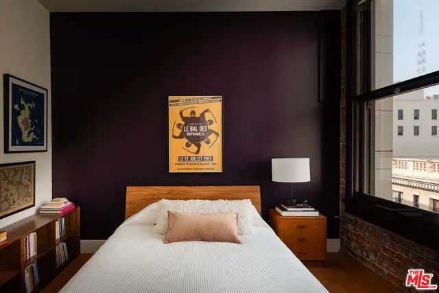 a bedroom with a bed and a lamp on dresser