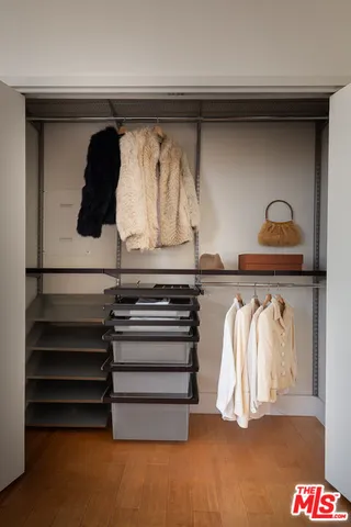a view of walk in closet with clothes and shoes
